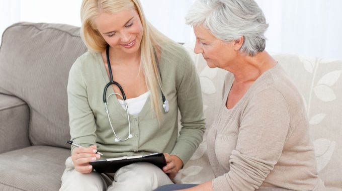 Social Worker Explaining Forms To An Elderly Client.