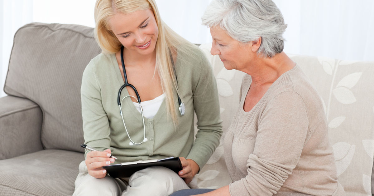 Social Worker Explaining Forms To An Elderly Client.